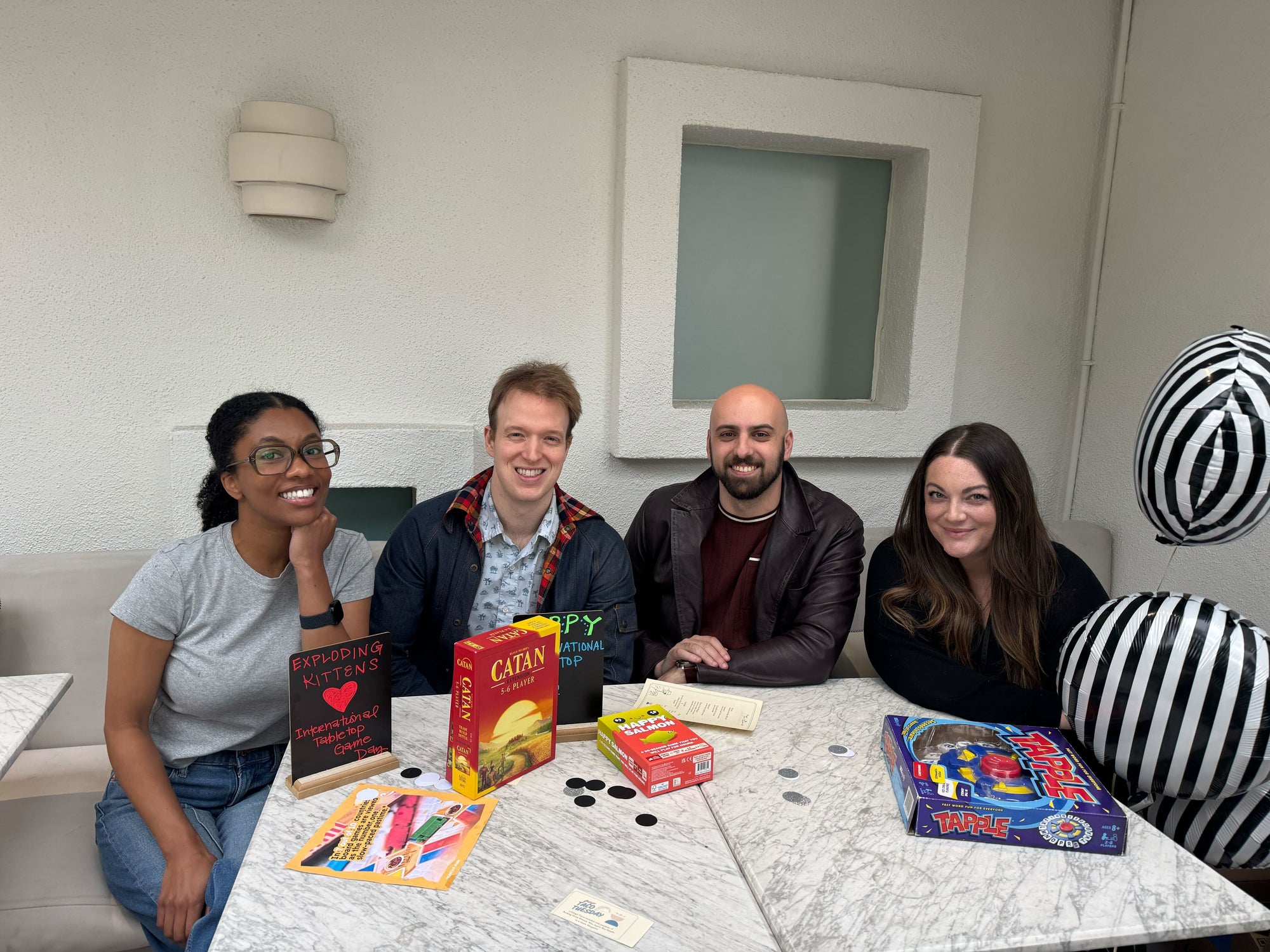 Four people playing a card game around a table 