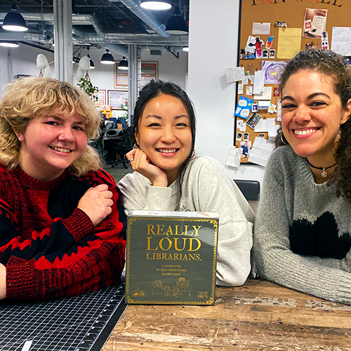 Three smiling women holding a Really Loud game box 