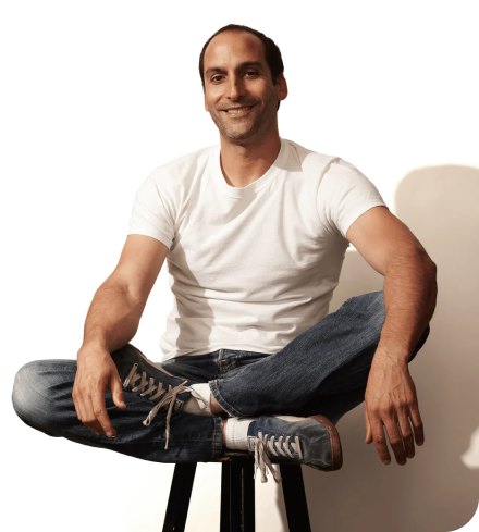 Man in a white t-shirt seated on a stool 